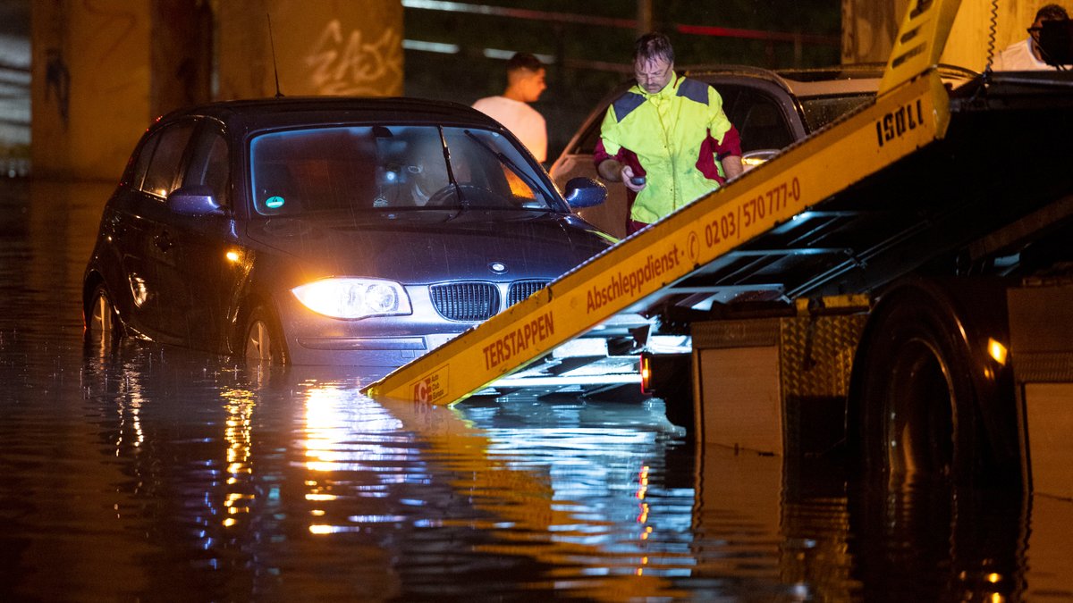 Ein Auto wird vom Abschleppdienst aus einer überfluteten Unterführung  in Nordrhein-Westfalen geborgen. 