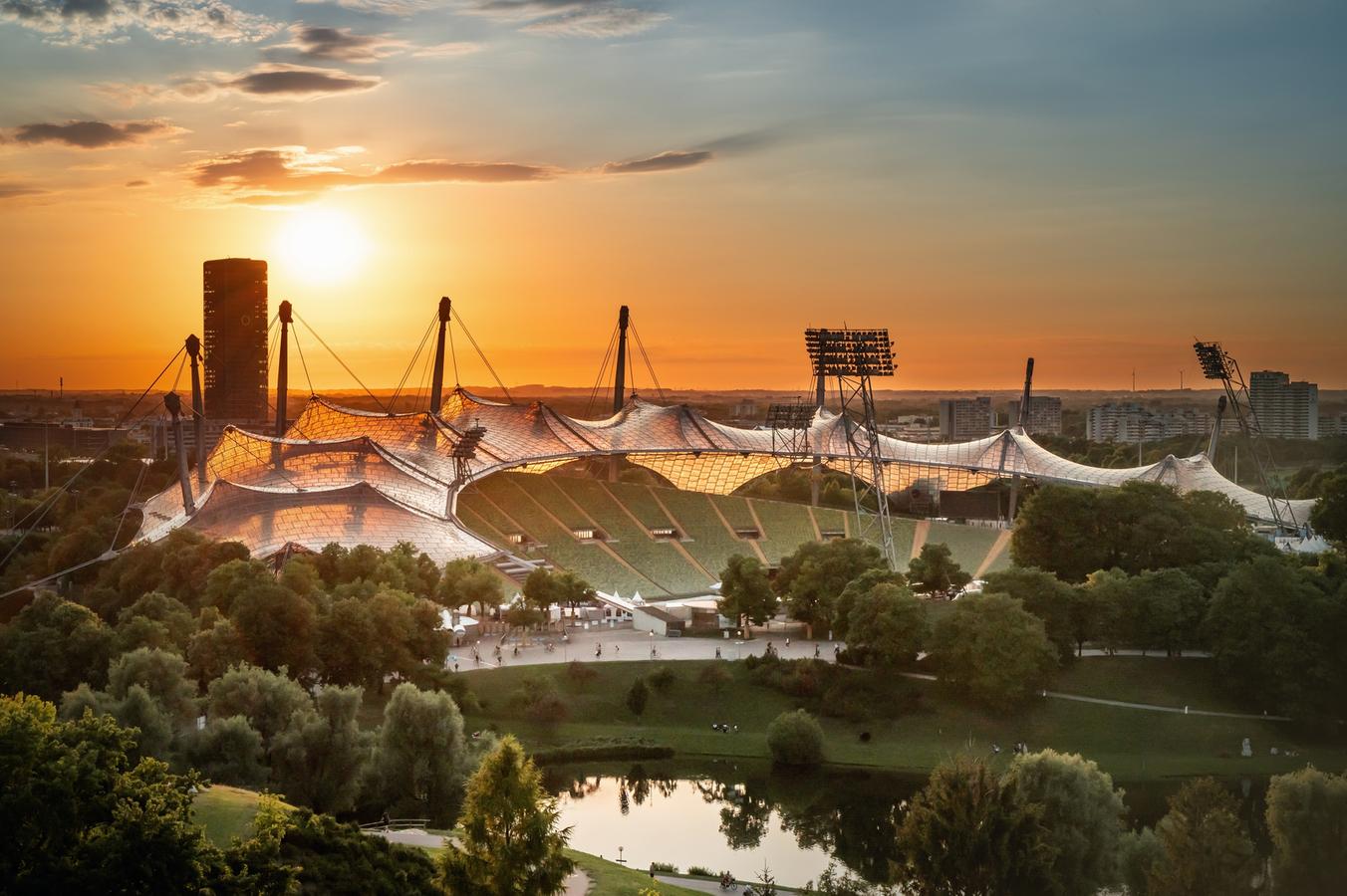 Tiefstehende Sonne über dem Olympiastadion in München mit dem O2-Tower im Hintergrund