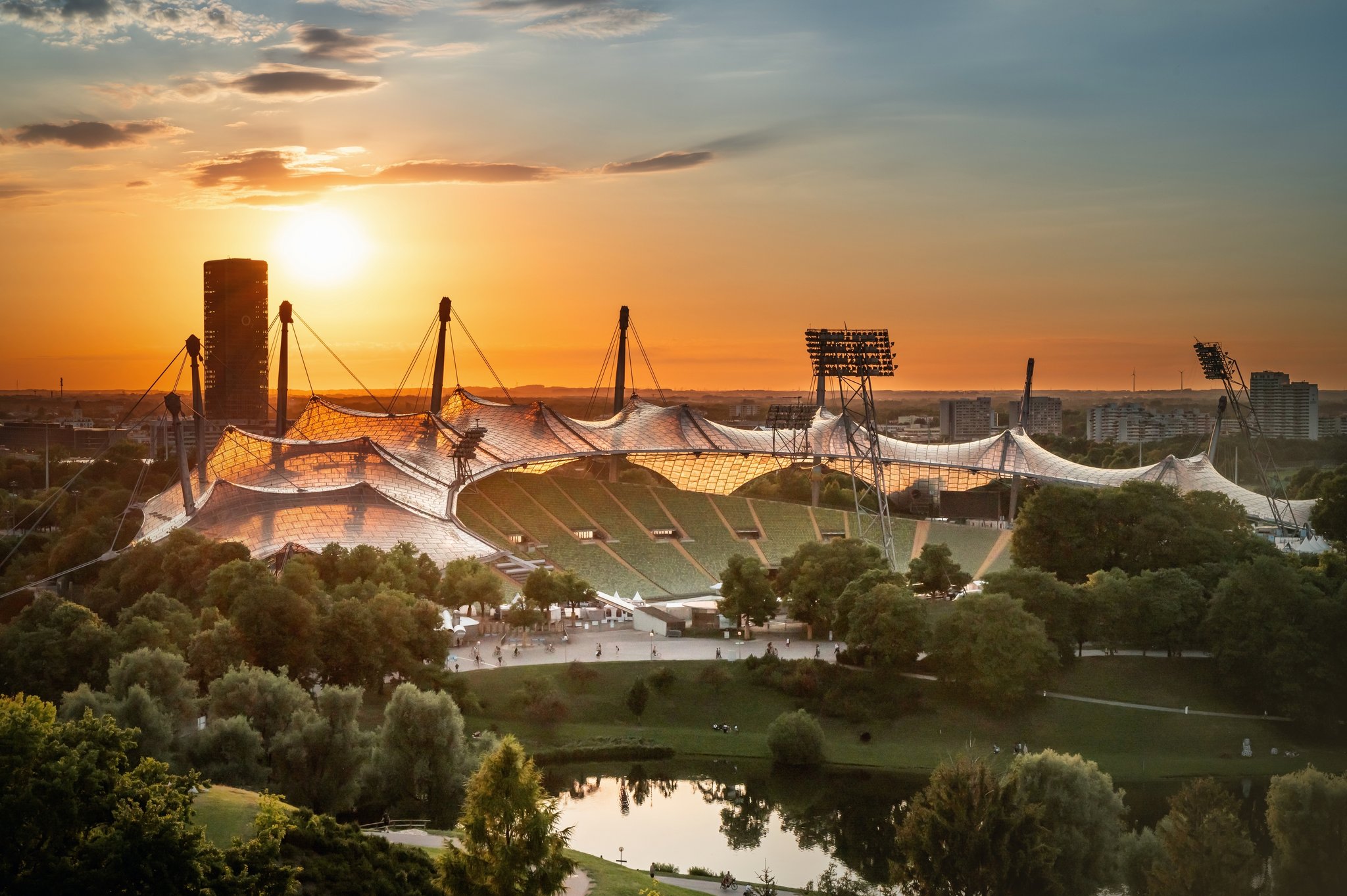 Tiefstehende Sonne über dem Olympiastadion in München mit dem O2-Tower im Hintergrund.