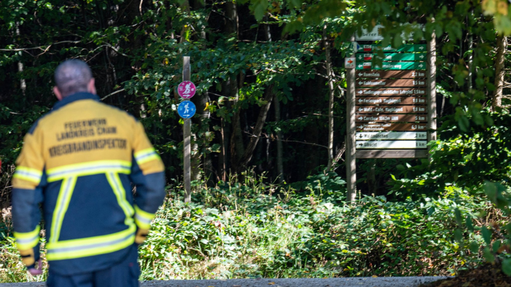 Ein Feuerwehrmann steht an einem Wanderweg.