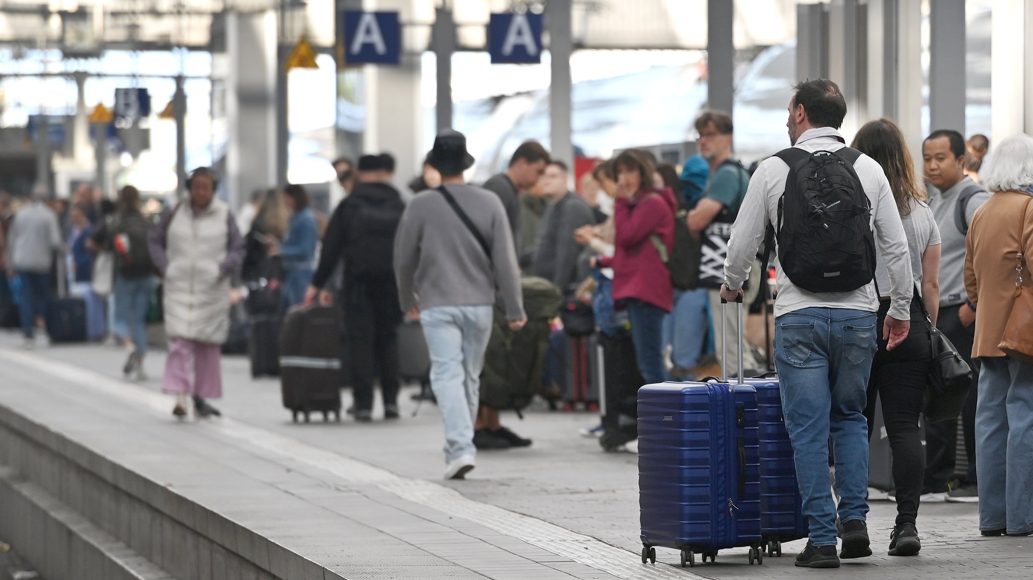 Viele Menschen warten auf einem Bahnsteig auf ihren Zug.