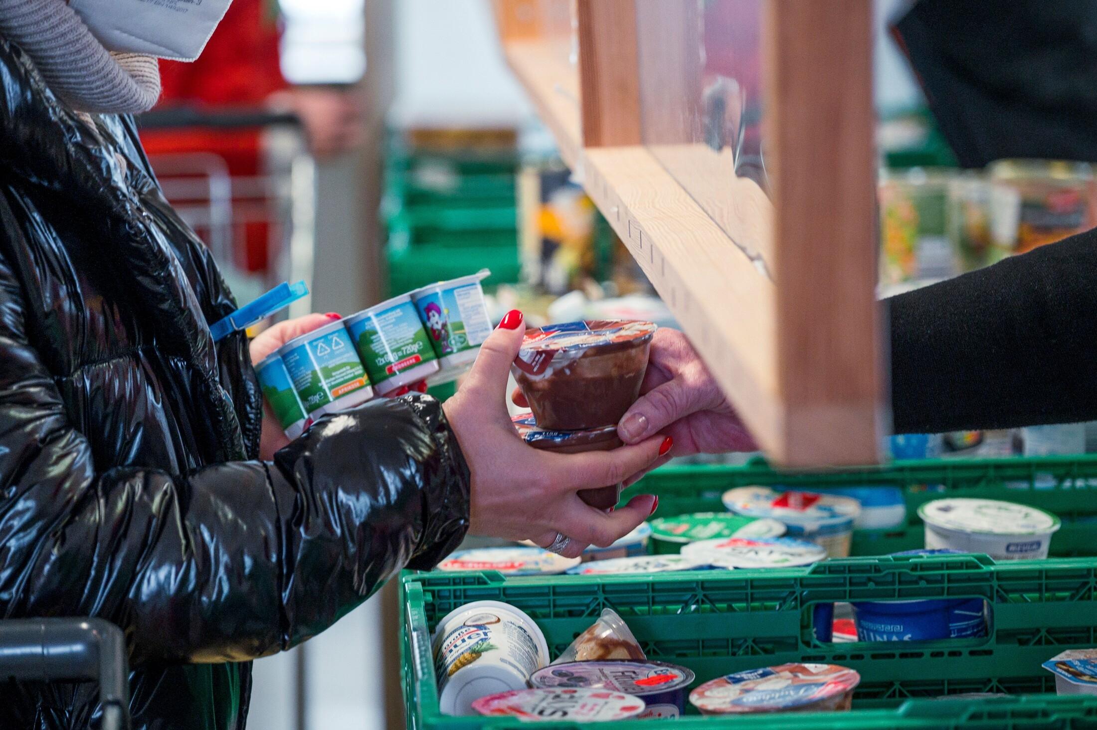Die Kundin einer Tafel bekommt Joghurt und Pudding.
