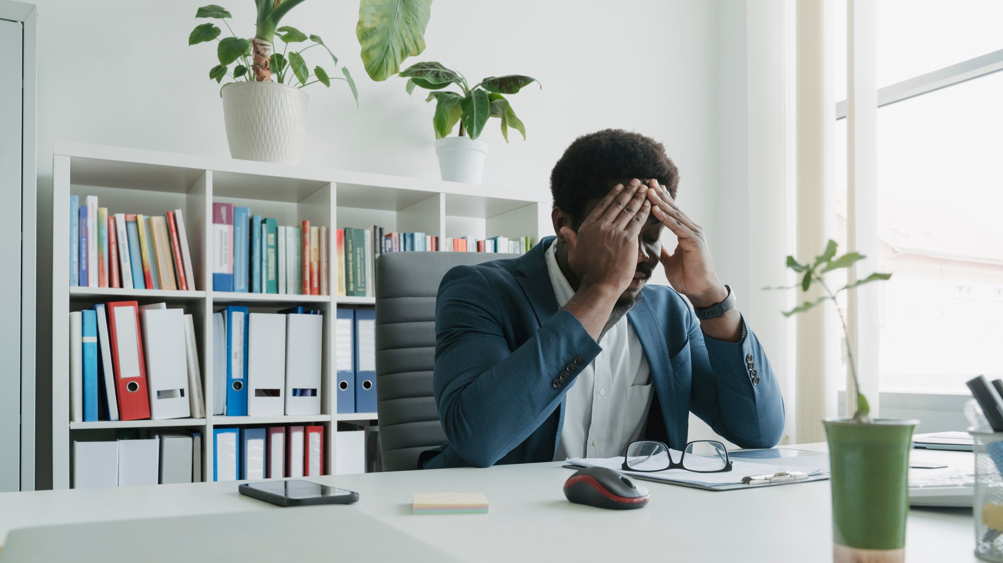 Ein Mann sitzt an einem Bürotisch. Er hält sich die Hände an den Kopf. | Bild: picture alliance / Westend61 | Ok Shu Ein Mann sitzt an einem Bürotisch. Er hält sich die Hände an den Kopf.