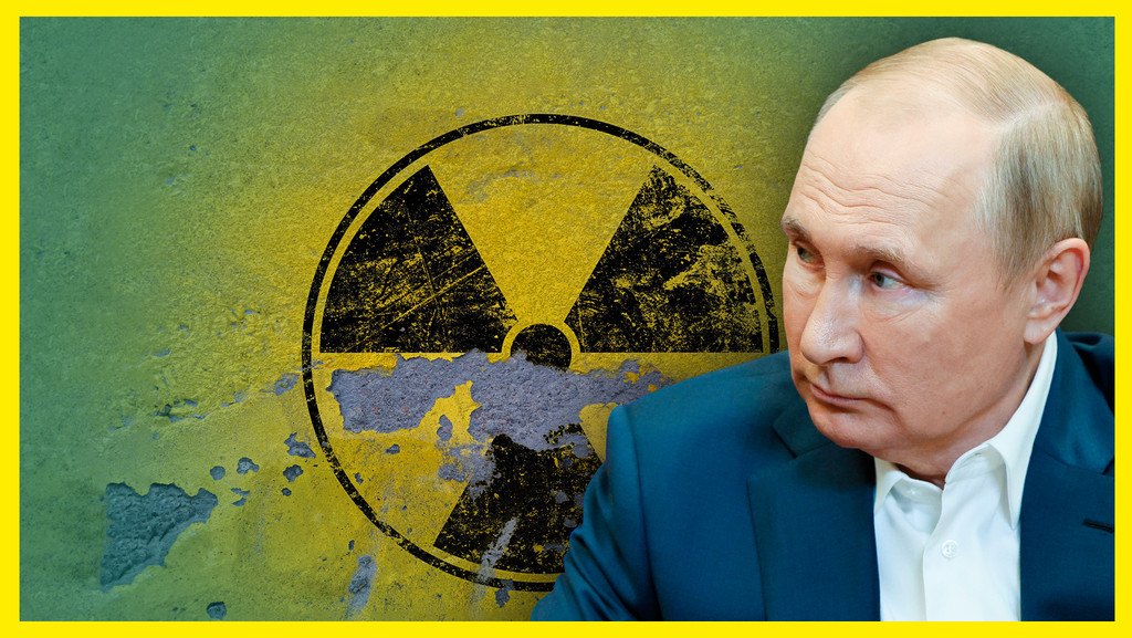 Ein Mann in Anzug und weißem Hemd, es ist der russische Präsident Wladimir Putin. Hinter ihm das Atom-Warnzeichen, es bröckelt von der Wand.