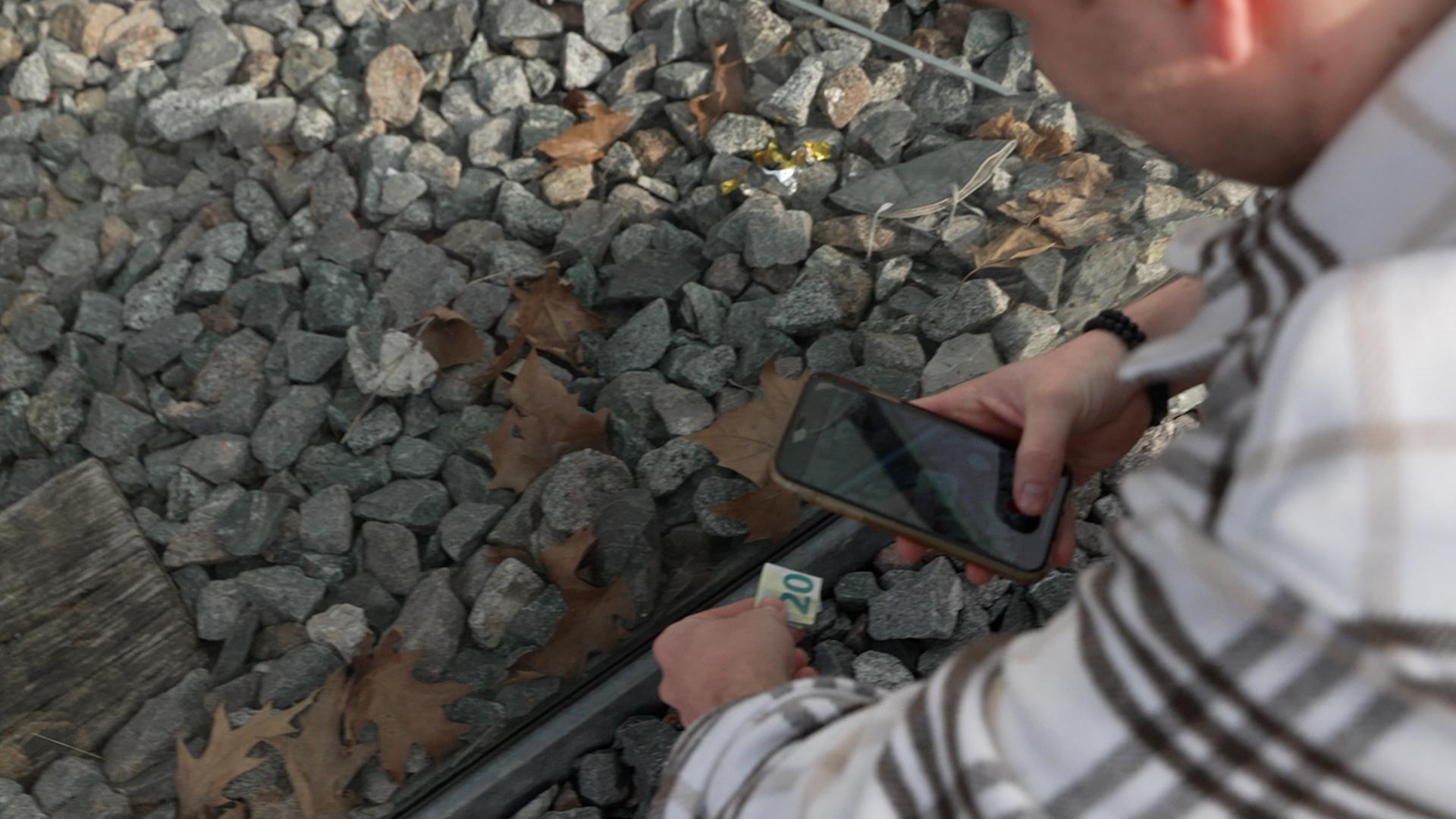 Ein Mann versteckt 20 Euro unter einem Stein.