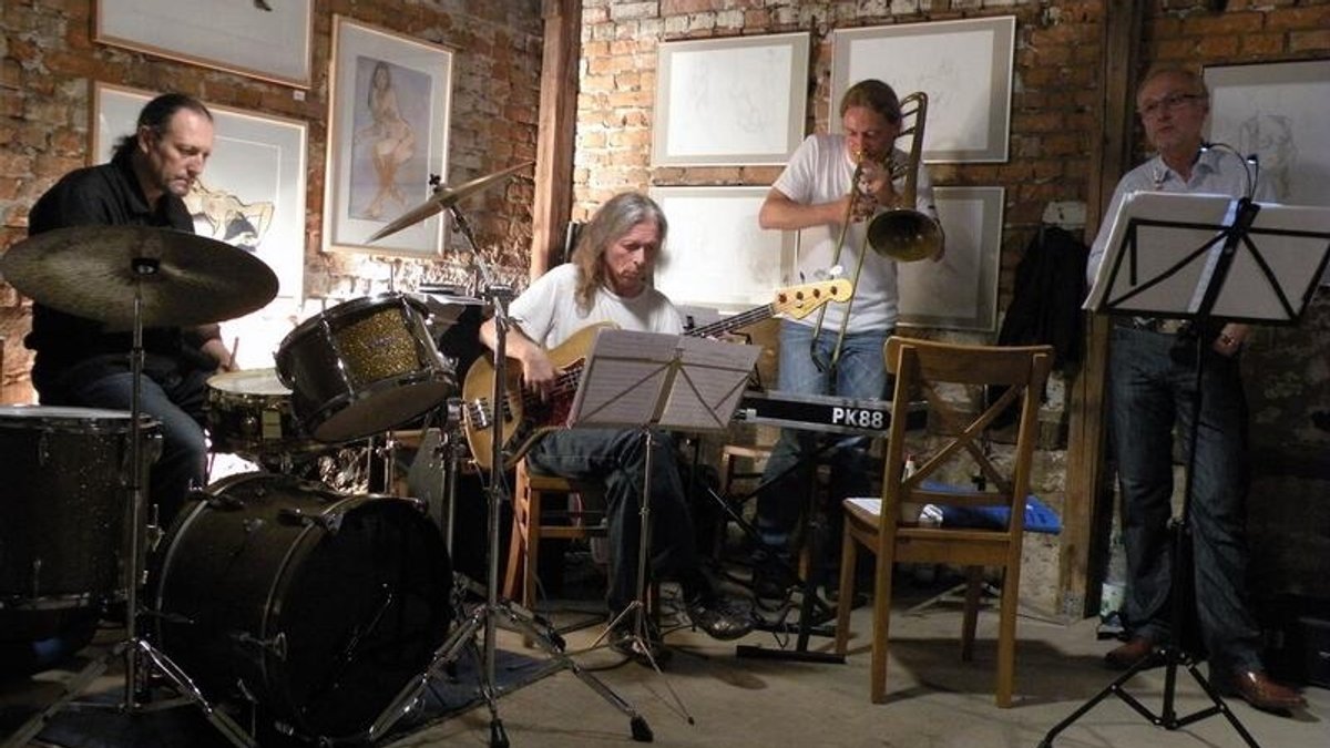 Die vier Bandmitglieder spielen an ihren Instrumenten vor einer Backsteinwand.
