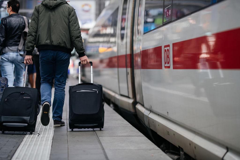 Reisende laufen an einem ICE vorbei.