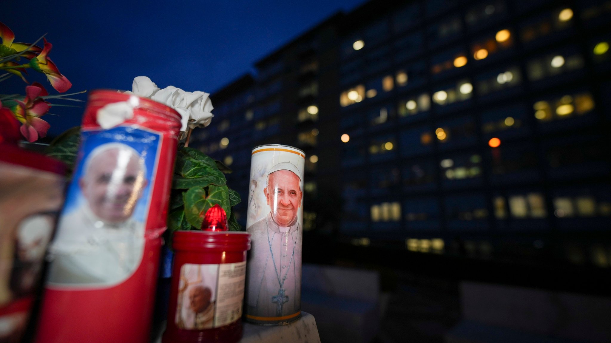 Kerzen mit Bildern von Papst Franziskus wurden unter der Statue des verstorbenen Papstes Johannes Paul II. vor der Poliklinik Agostino Gemelli in Rom niedergelegt, wo der Franziskus behandelt wird.