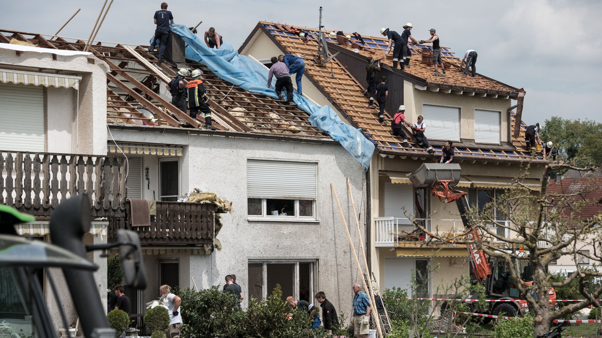 Helfer decken Hausdächer mit Folien ab, nachdem ein Tornado die Ziegel weggerissen hat. | Bild: picture alliance / Lukas Barth Helfer decken Hausdächer mit Folien ab, nachdem ein Tornado die Ziegel weggerissen hat.