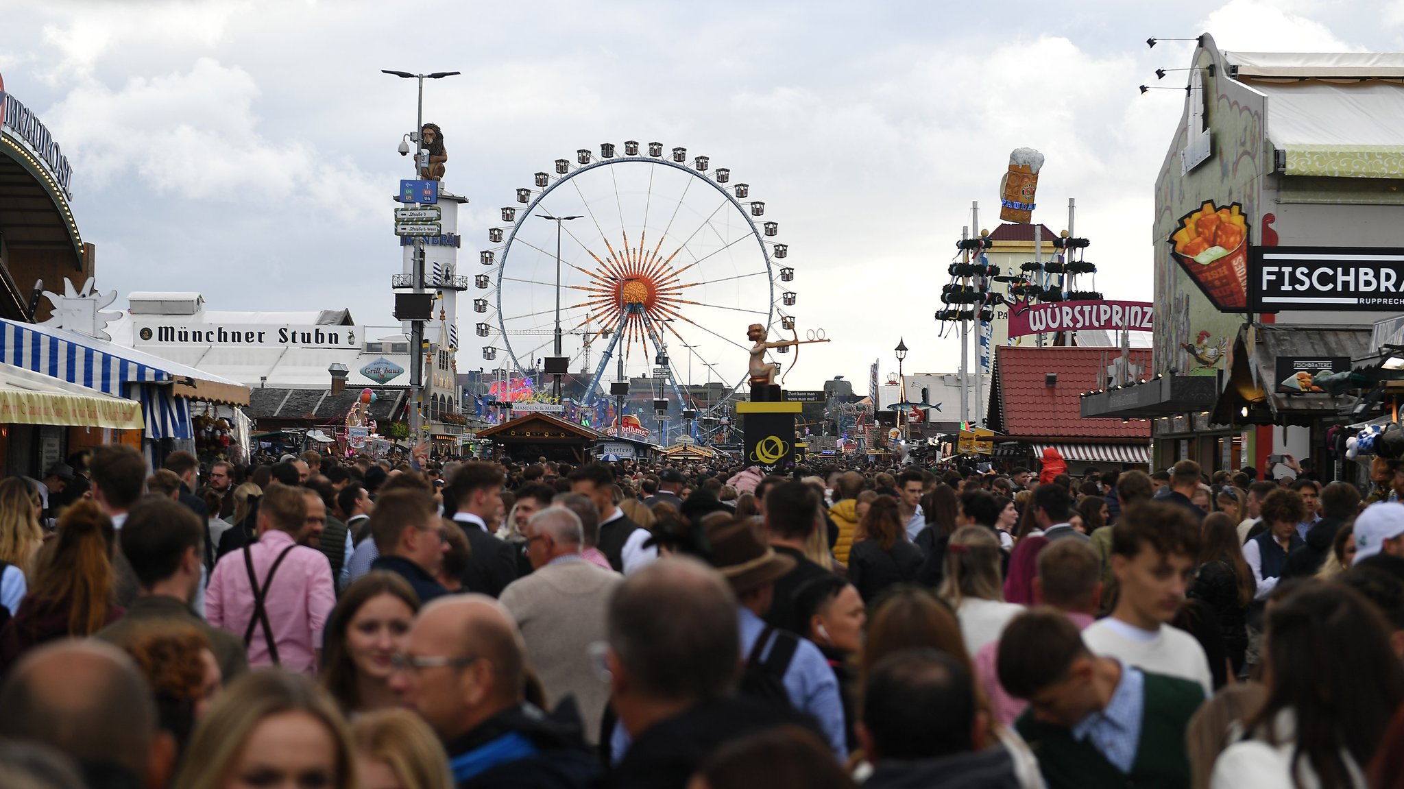 Dicht gedrängt gehen Gäste an einem regnerischen Tag über die Wiesn