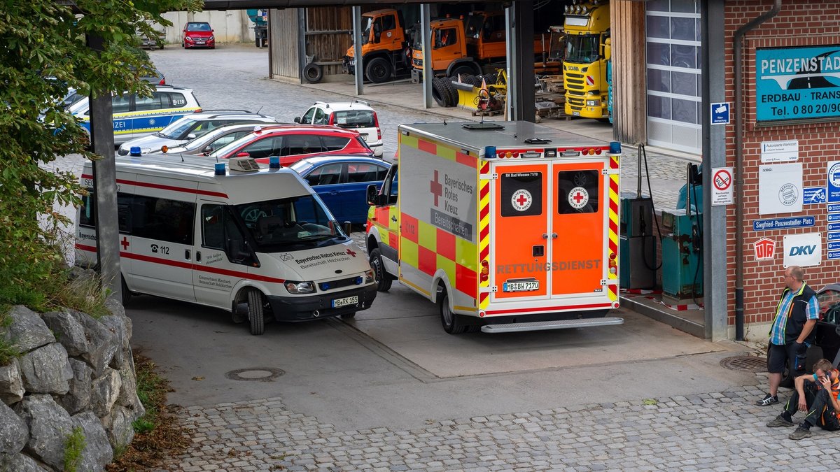 25.07.2023, Bayern, Weyarn: Ein Krankenwagen steht in der Einfahrt eines Unternehmens. Bei einem Arbeitsunfall in einer Entsorgungsfirma in Oberbayern sind drei Männer in einem Kanalsystem ertrunken. Foto: Peter Kneffel/dpa - ACHTUNG: Die Kennzeichennummer aus rechtlichen Gründen gepixelt +++ dpa-Bildfunk +++