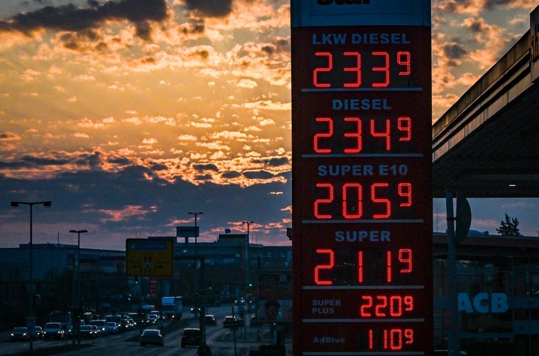 (Symbolbild)  Auf einer Anzeigetafel einer Tankstelle stehen bei Sonnenaufgang die aktuellen Preise für Benzin und Diesel.