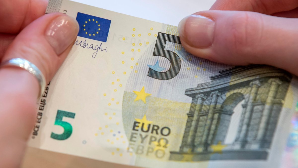 Eine Frau hält einen 5-Euro-Schein in der Hand.