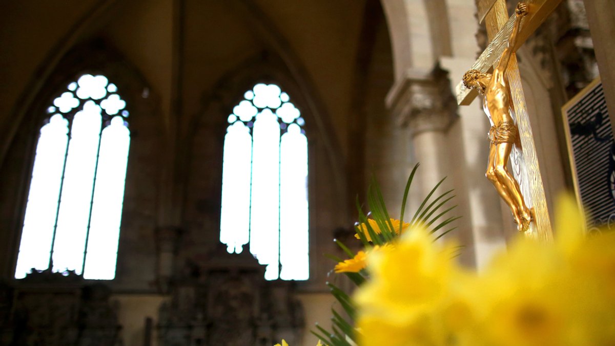 Ein Jesuskreuz und ein Strauß Osterglocken stehen im Dom zu Magdeburg Sankt Mauritius und Katharina.