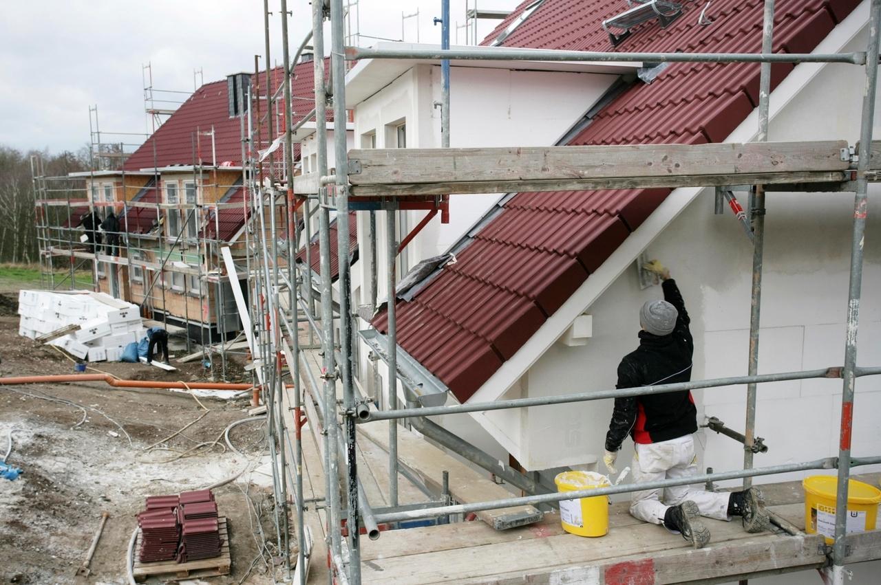 Handwerker bringt Aussenisolierung wird an die Wand eines Rohbaus an