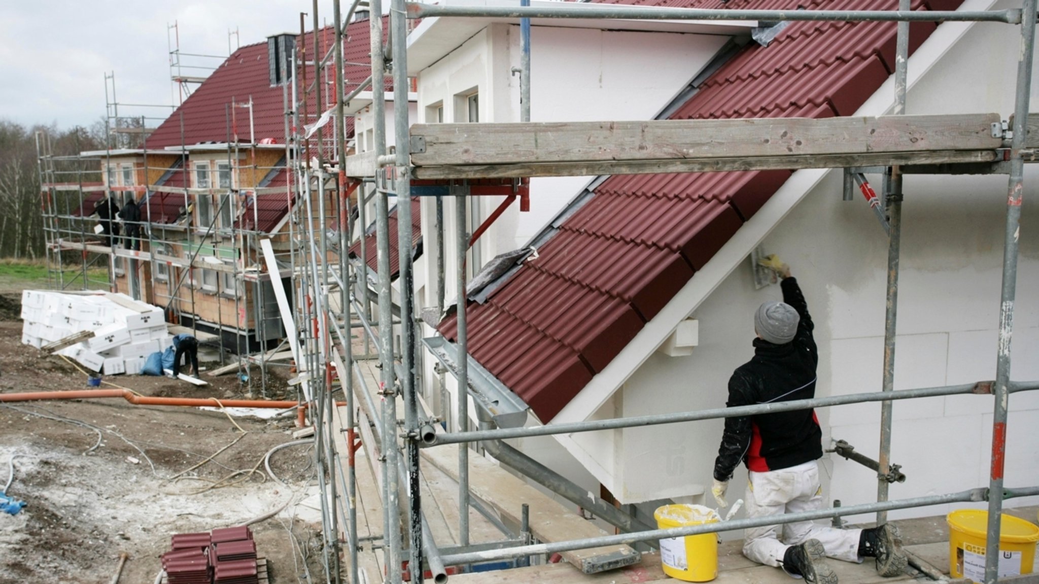 Handwerker bringt Aussenisolierung wird an die Wand eines Rohbaus an