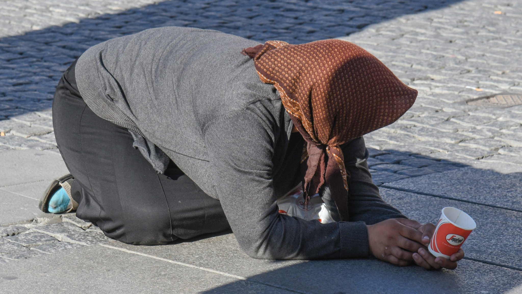 Eine Frau bettelt in Demutshaltung in der Innenstadt in München um ein Almosen.