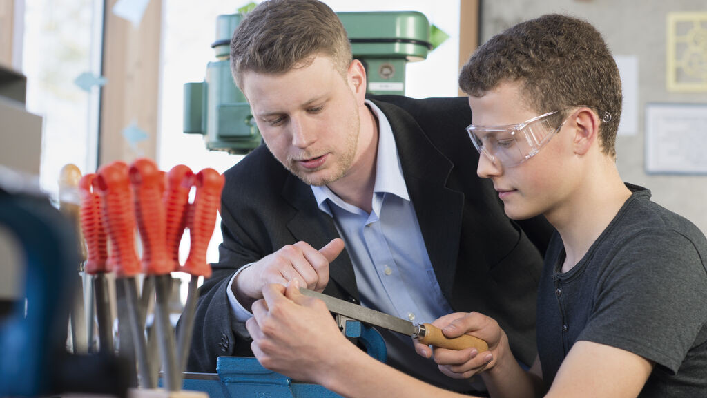 Zwei junge Männer in einer Werkstatt feilen an einem Metallstück (Symbolbild).