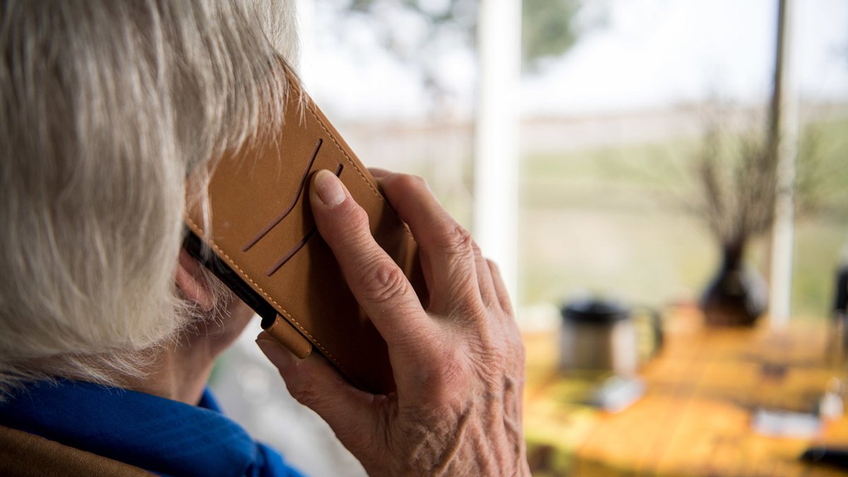 Rentnerin hält Handy ans Ohr.
