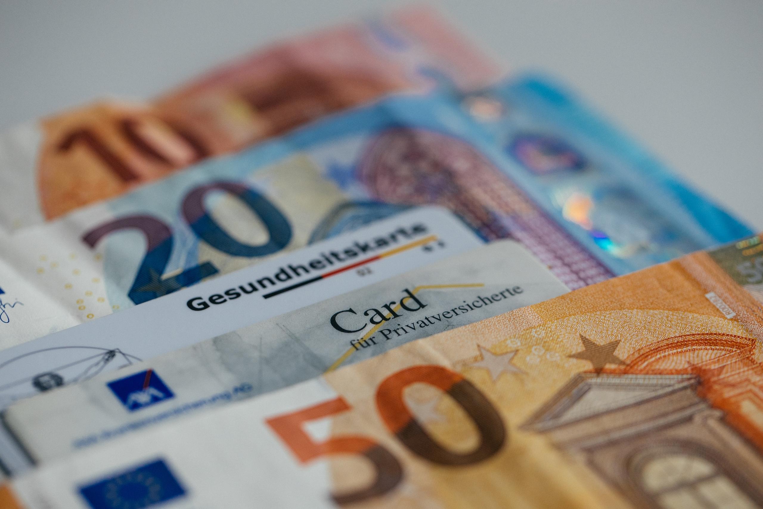 Gesundheitskarten liegen mit Geld auf dem Tisch.