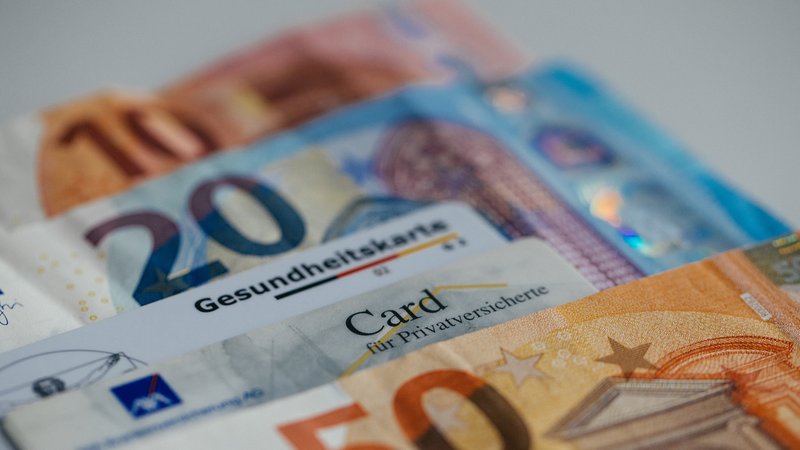Gesundheitskarten liegen mit Geld auf dem Tisch. | Bild: BR/Julia Müller Gesundheitskarten liegen mit Geld auf dem Tisch.