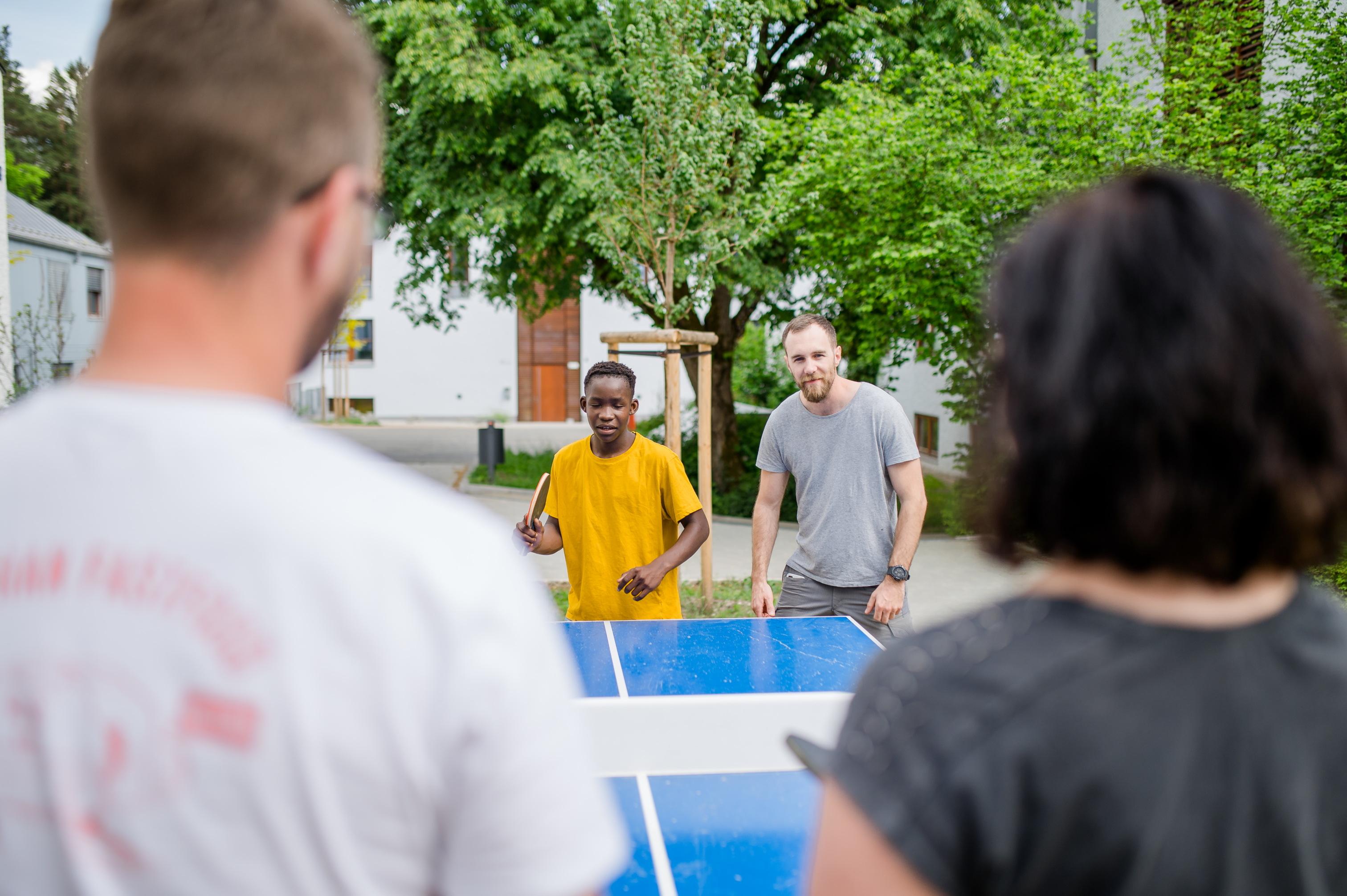 Vier Personen spielen Tischtennis. 
