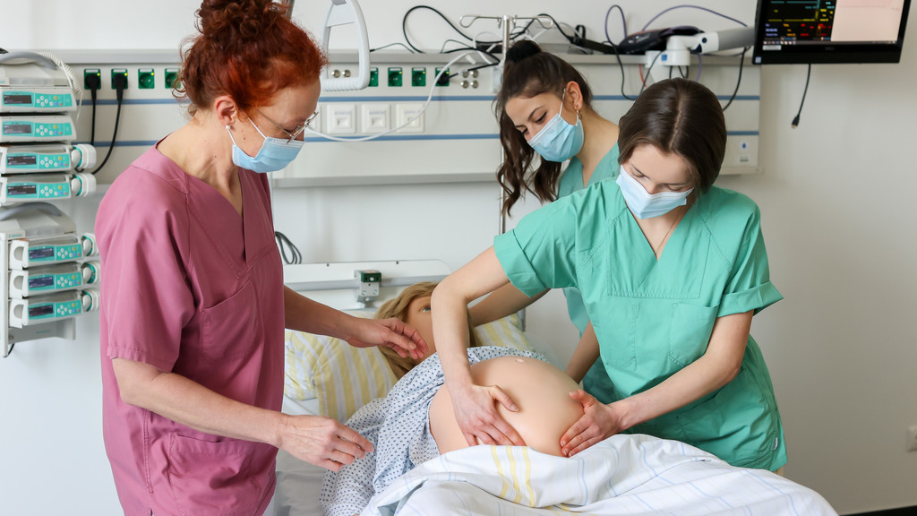 Junge Frauen, die Hebammenkunde studieren, bei einer Übung. 
