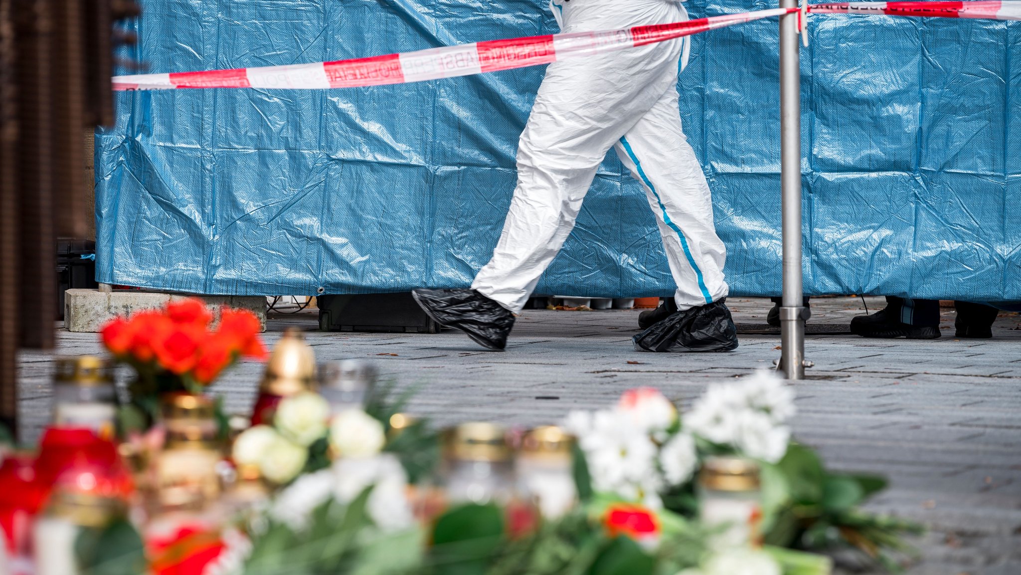 Vor einem Blumenaden in Lichtenfels liegen Grabkerzen und Blumen am Boden. Im Hintergrund ist ein Absperrband der Polizei.