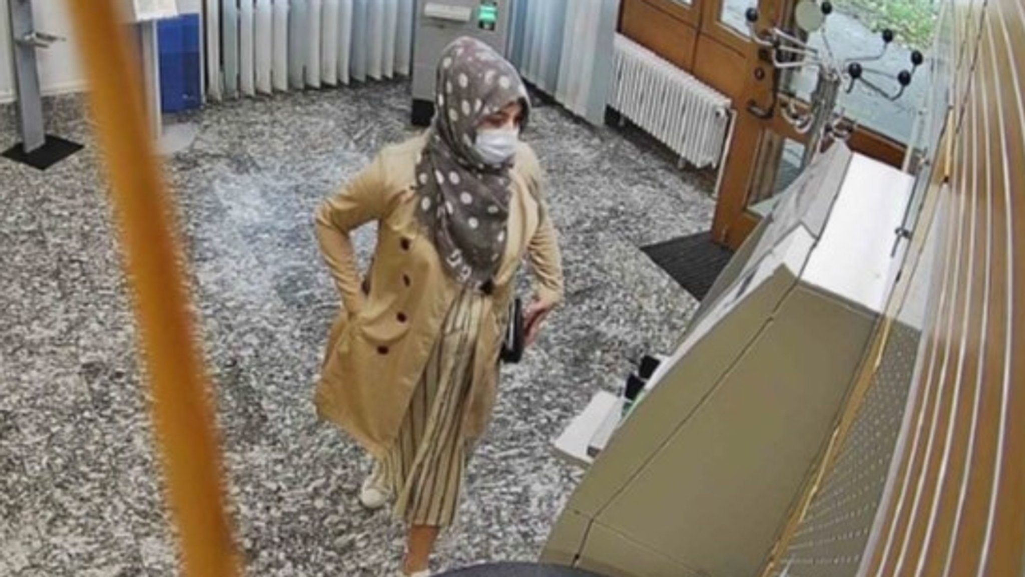 Eine Frau steht vor einem Geldautomaten in einer Bankfiliale.