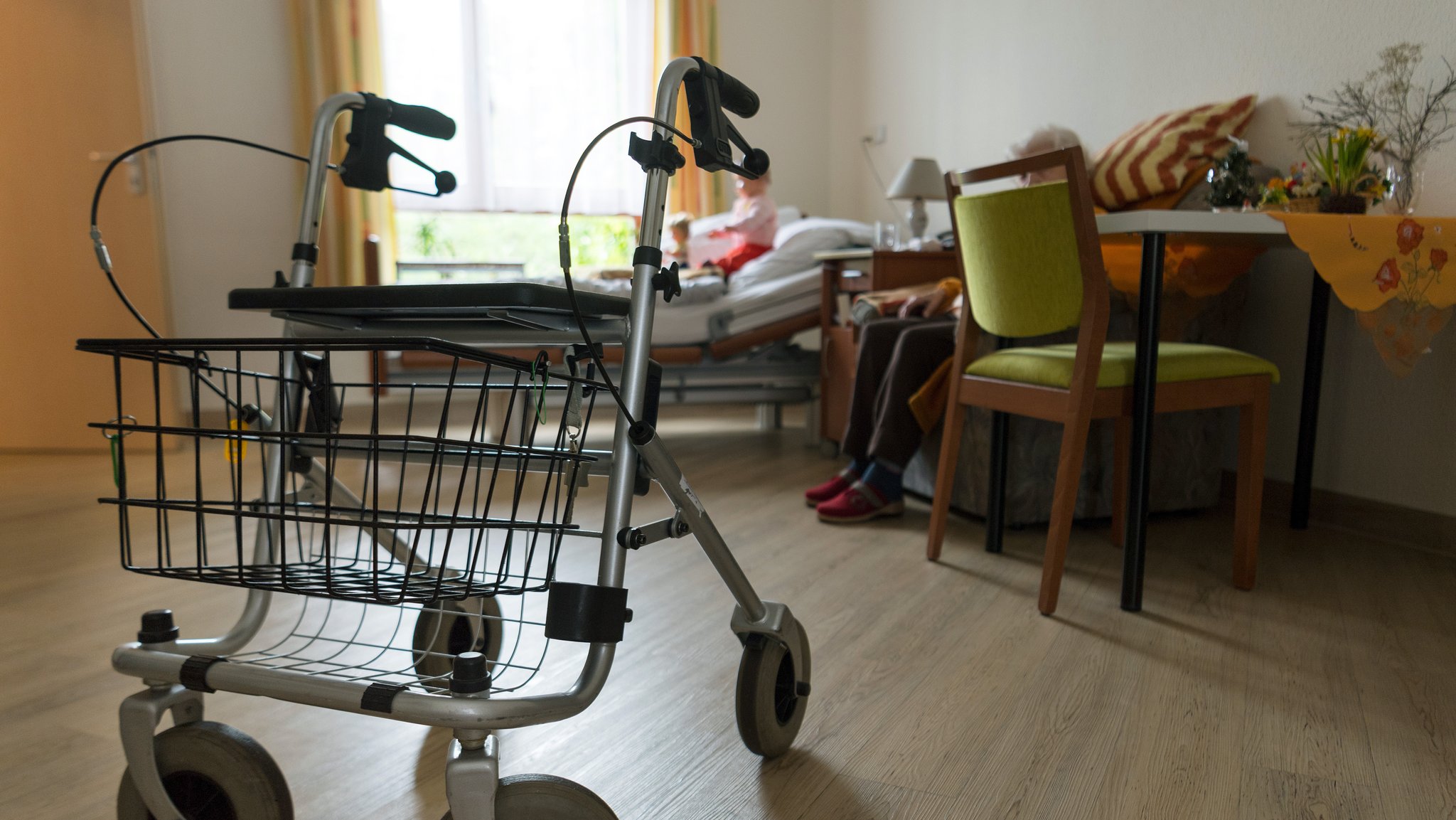 Ein Rollator steht im Raum einer Seniorin.