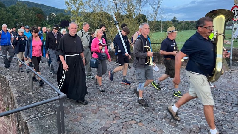 Wallfahrerinnen und Wallfahrer der Würzburger Kreuzberg-Wallfahrt beim Laufen. Dazwischen Bruder Maximilian in Kutte. | Bild: Rebecca Reljac / Bistum Würzburg Wallfahrerinnen und Wallfahrer der Würzburger Kreuzberg-Wallfahrt beim Laufen. Dazwischen Bruder Maximilian in Kutte.