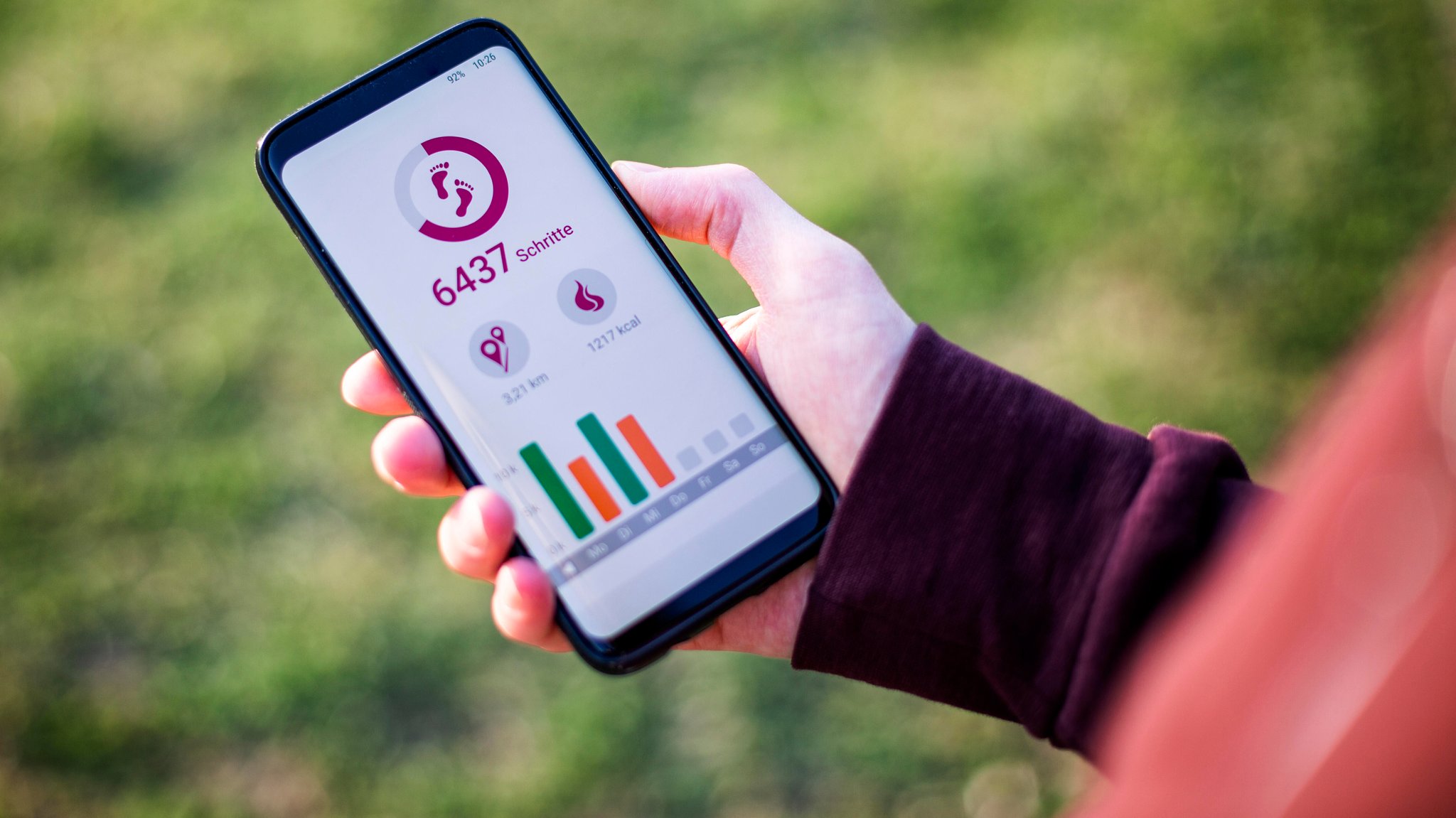 Eine Hand hält ein Handy, auf dem die Schrittanzahl zu lesen ist