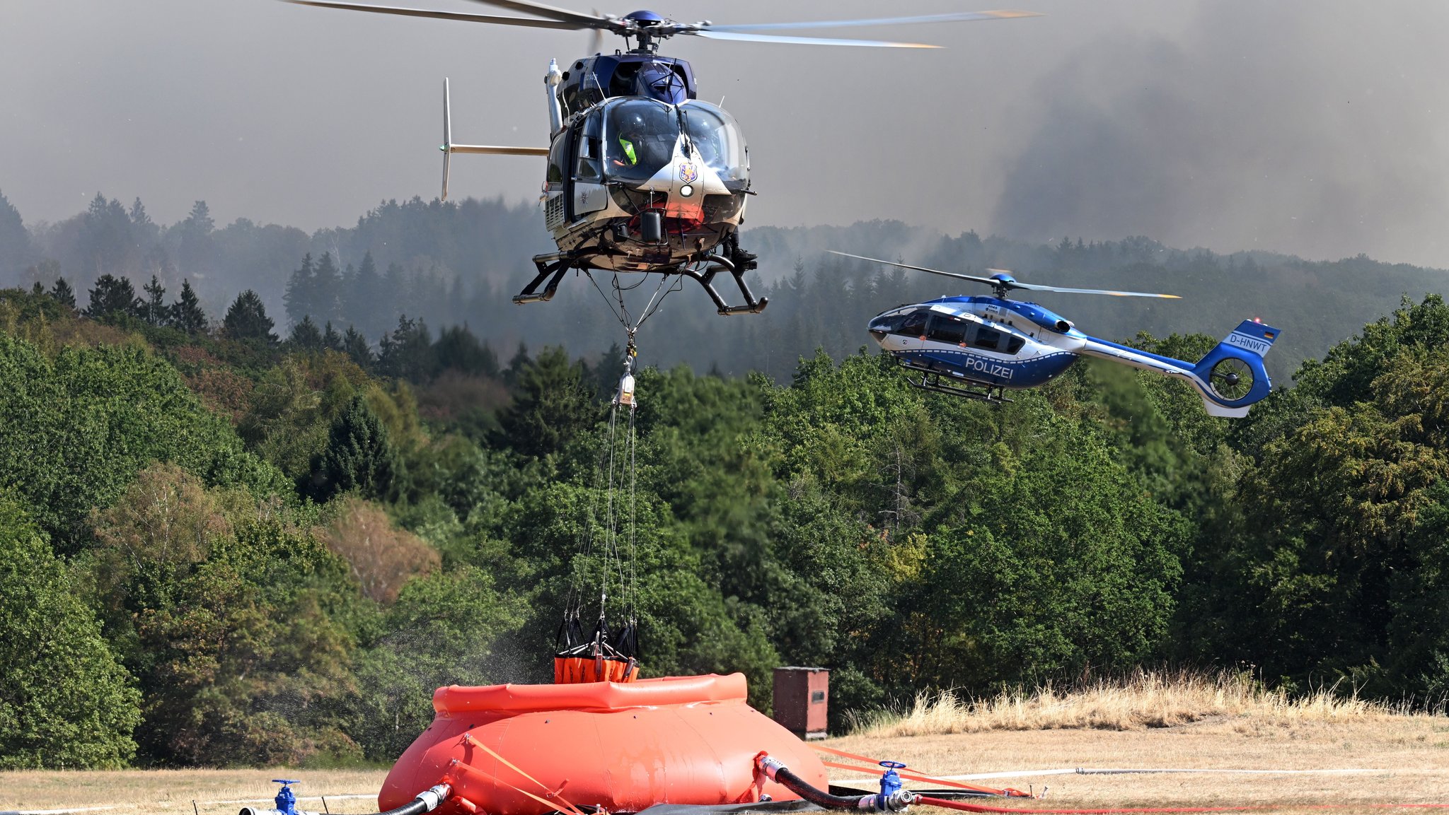 Hubschrauber nimmt bei Löschwasserbehälter auf. | Bild: picture alliance/dpa | Federico Gambarini Hubschrauber nimmt bei Löschwasserbehälter auf.