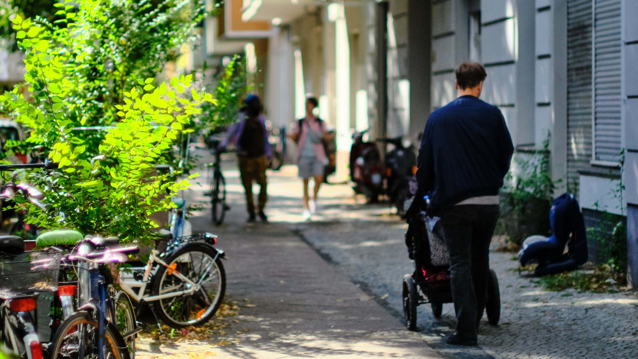 Berlin, August 2021: Ein Mann schiebt einen Kinderwagen eine Straße im Stadtteil Neukölln entlang.