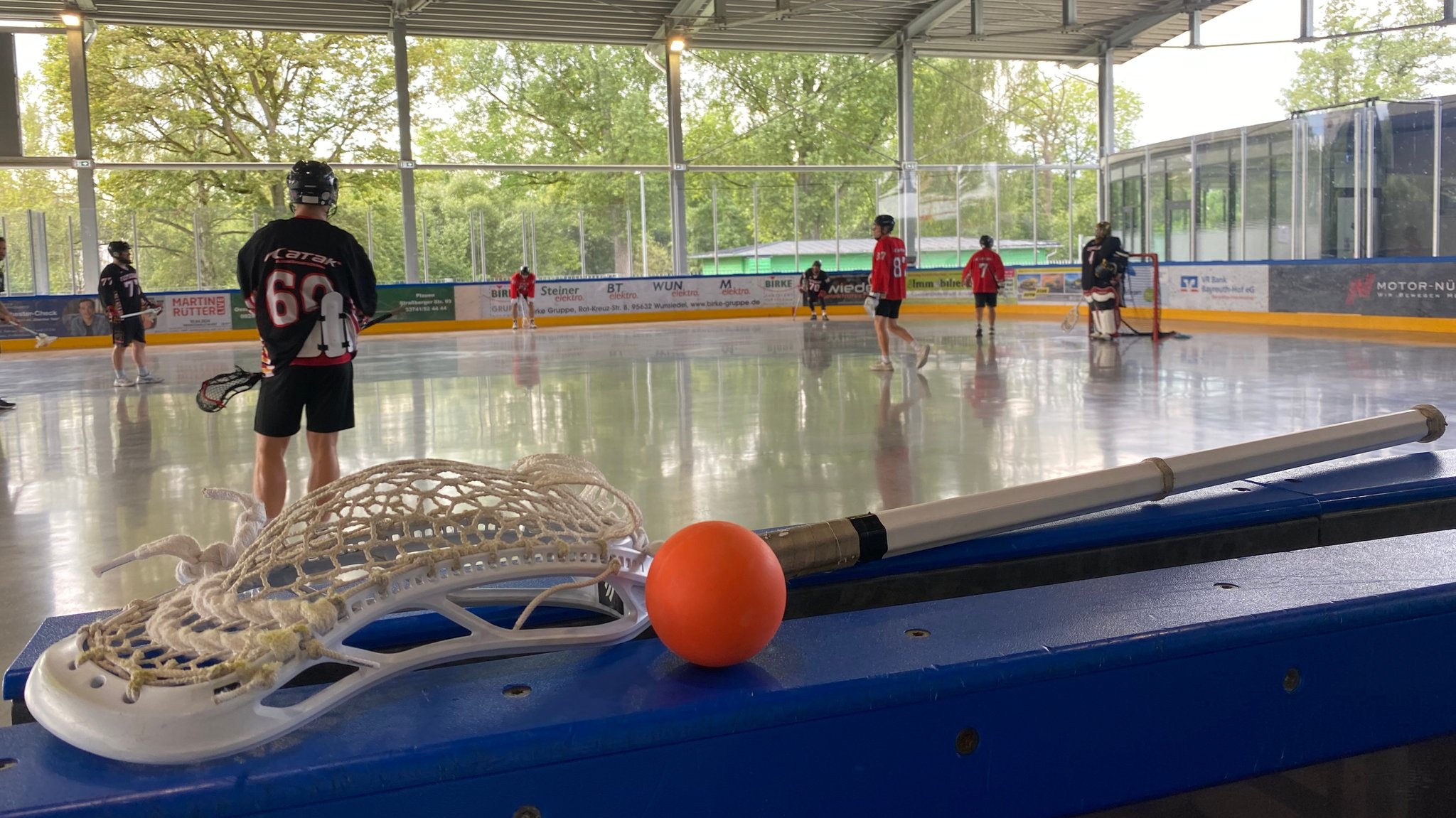 Ein Lacrosse-Schläger und ein Ball liegen beim Training der Nationalmannschaft in Hof auf einer Bande.