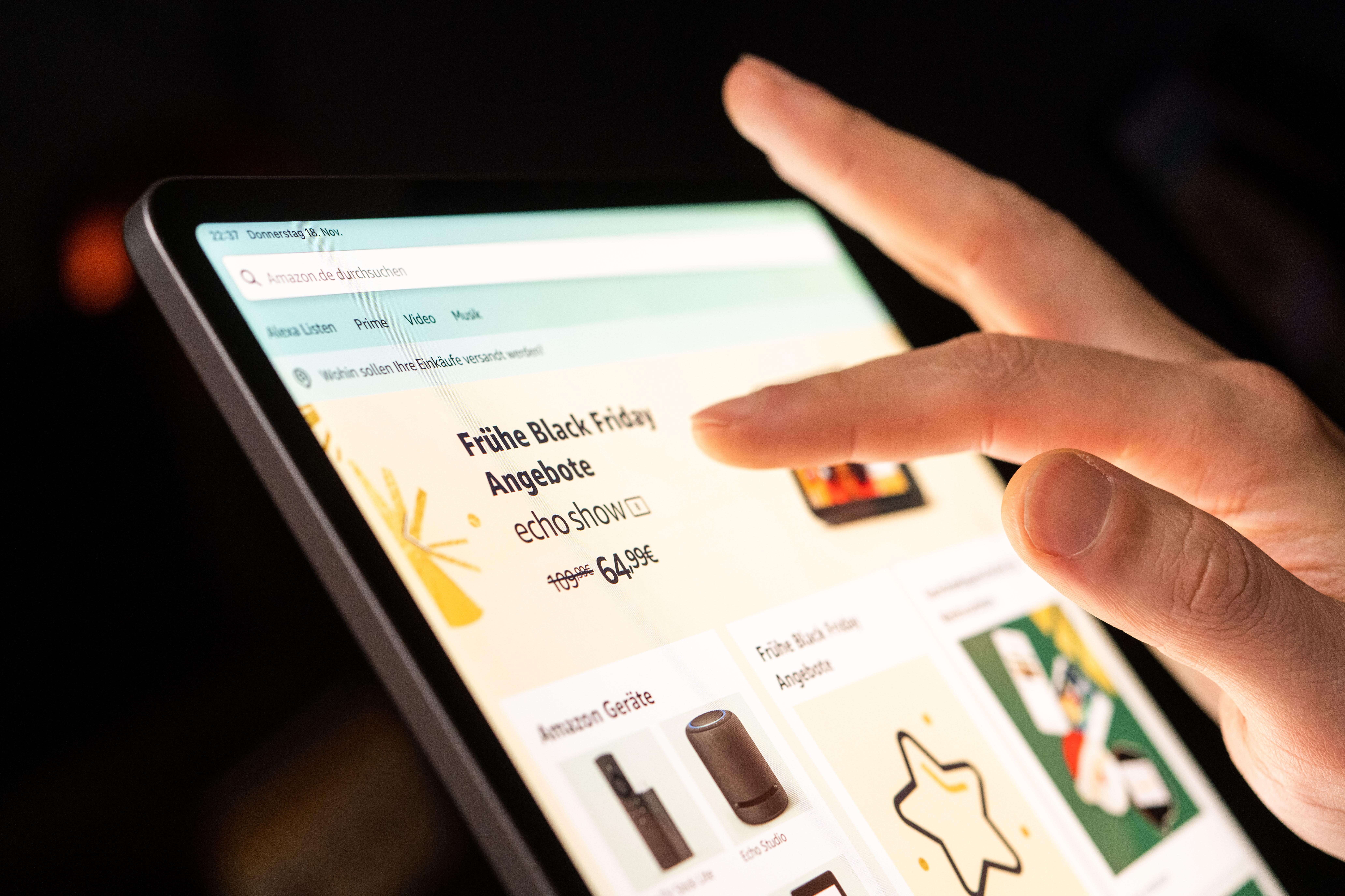 Eine Hand wischt über ein Tablet, auf dem eine Website Black-Friday-Angebote verspricht.