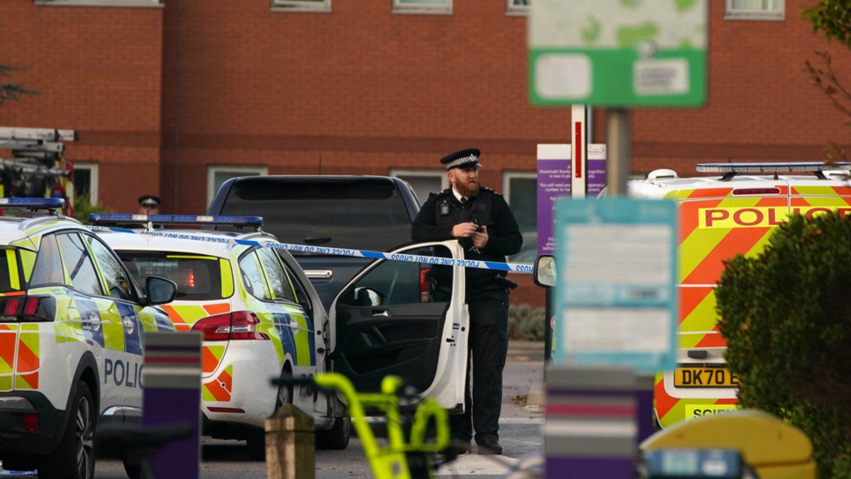 Ein Polizist steht zwischen Autos vor der Frauenklinik in Liverpool, nachdem dort bei einer Explosion eines Autos ein Mensch ums Leben gekommen ist (14.11.21). 