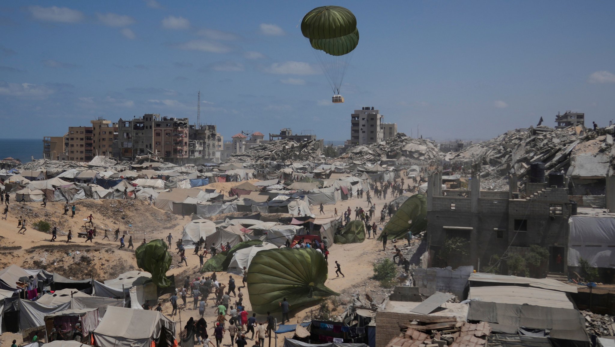 07.08.2025, Palästinensische Gebiete, Gaza-Stadt: Palästinenser beeilen sich, humanitäre Hilfsgüter einzusammeln, die mit Fallschirmen in Gaza-Stadt im nördlichen Gazastreifen abgeworfen wurden.