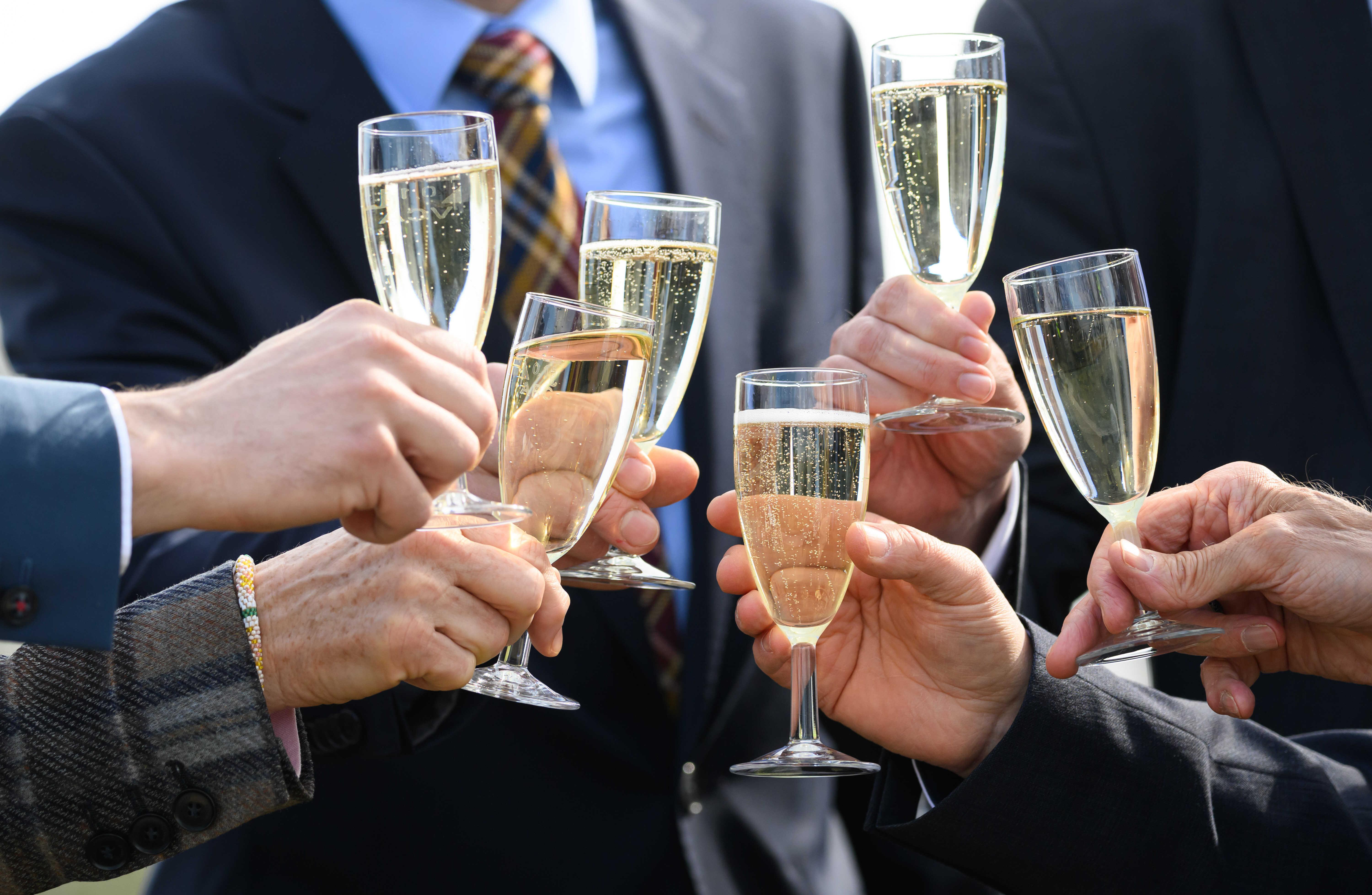 Symbolbild: Menschen im Anzug stoßen mit Champagner an.