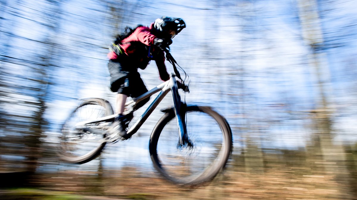 Symbolbild: Ein Mountainbiker fährt durch einen Wald.