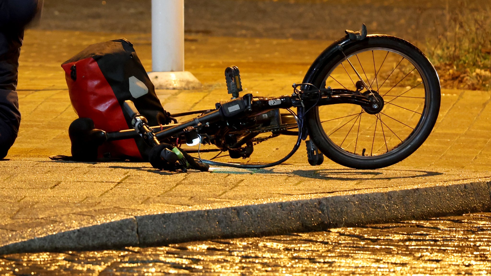 Fahrrad einer gestürzten Radfahrerin liegt auf einem vereisten Bürgersteig