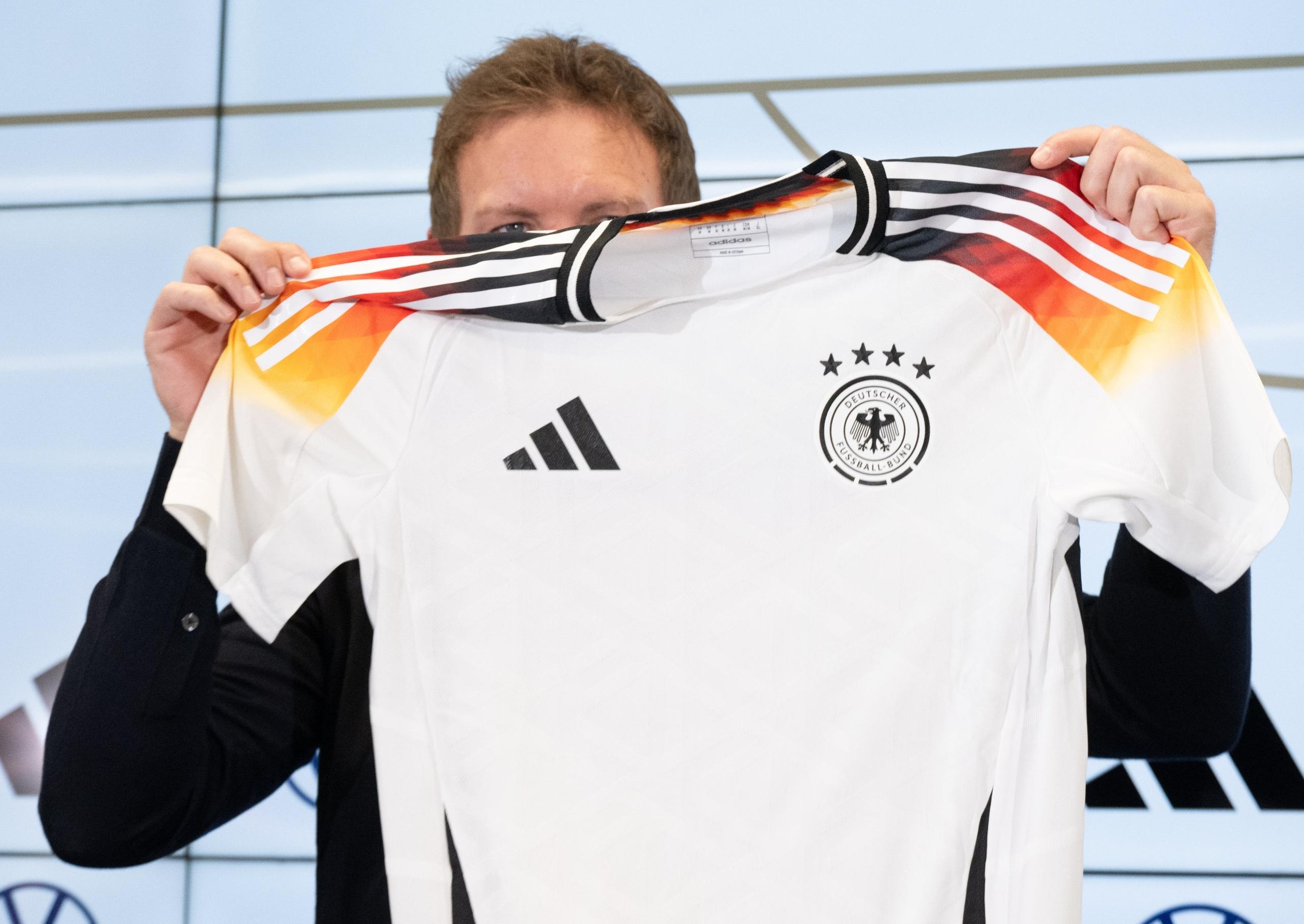 ARCHIV - 14.03.2024, Hessen, Frankfurt/Main: Bundestrainer Julian Nagelsmann hält auf einer Pressekonferenz das neue offizielle EM-Trikot des DFB-Teams hoch. Nagelsmann stellte den Kader für die Testländerspiele Ende März vor. Die DFB-Auswahl spielt am 23. März in Lyon gegen Frankreich und am 26. März in Frankfurt gegen die Niederlande. (zu "Nike statt Adidas ab 2027: Ausrüster-Revolution beim DFB") 