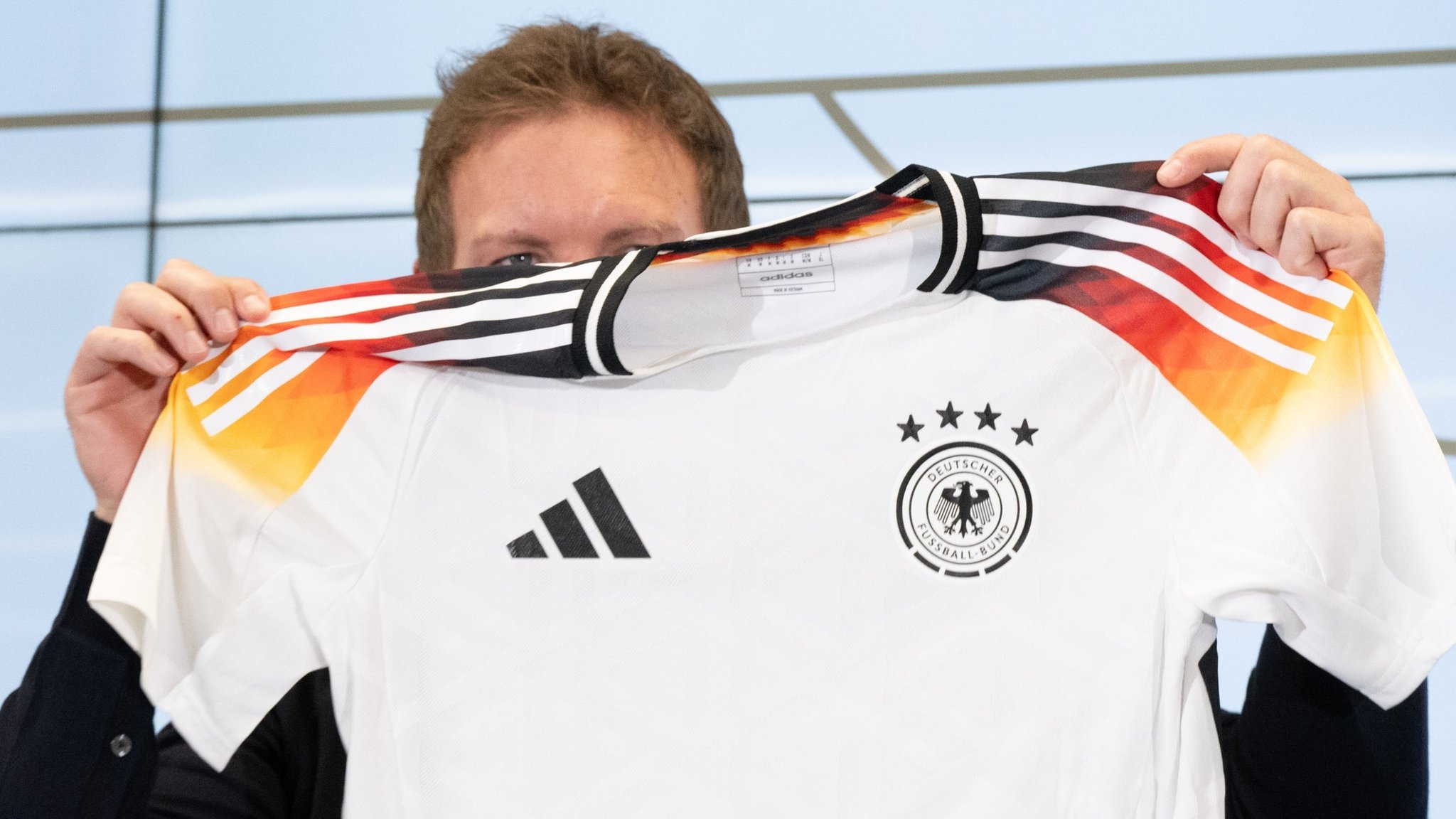 ARCHIV - 14.03.2024, Hessen, Frankfurt/Main: Bundestrainer Julian Nagelsmann hält auf einer Pressekonferenz das neue offizielle EM-Trikot des DFB-Teams hoch. Nagelsmann stellte den Kader für die Testländerspiele Ende März vor. Die DFB-Auswahl spielt am 23. März in Lyon gegen Frankreich und am 26. März in Frankfurt gegen die Niederlande. (zu "Nike statt Adidas ab 2027: Ausrüster-Revolution beim DFB") 