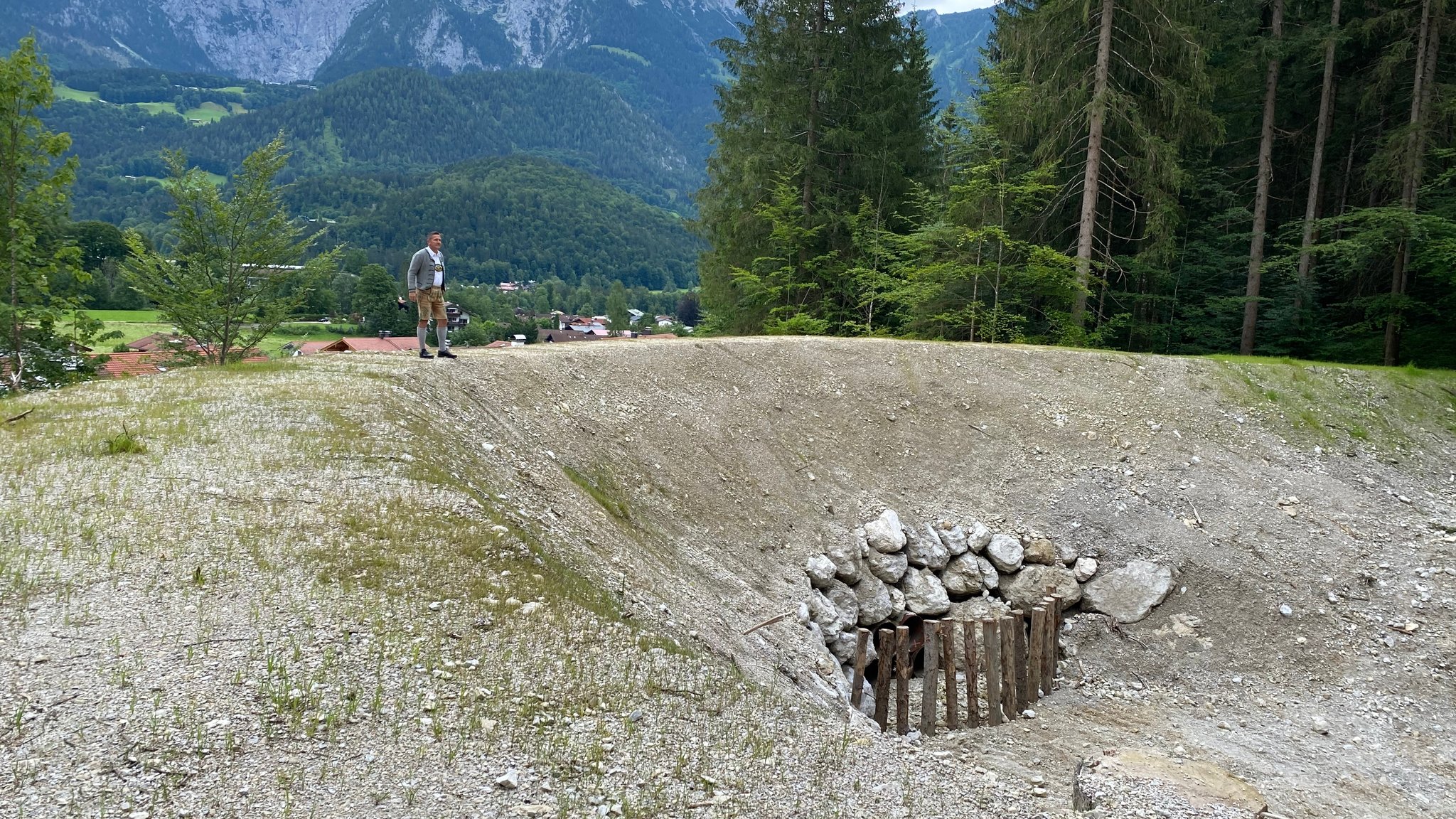 Ein Mann steht auf einem Erdwall und blickt auf das neue Auffangbecken, das die Siedlung vor Muren schützen soll.