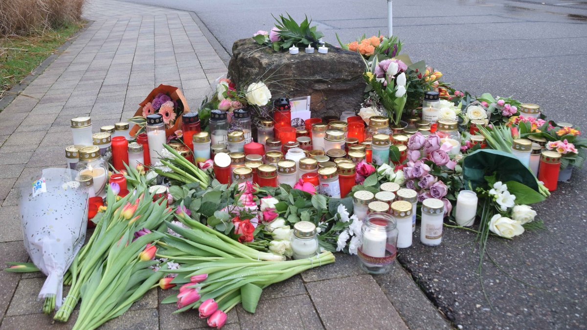 Blumen und Kerzen zum Gedenken an das Opfer liegen vor der Schule