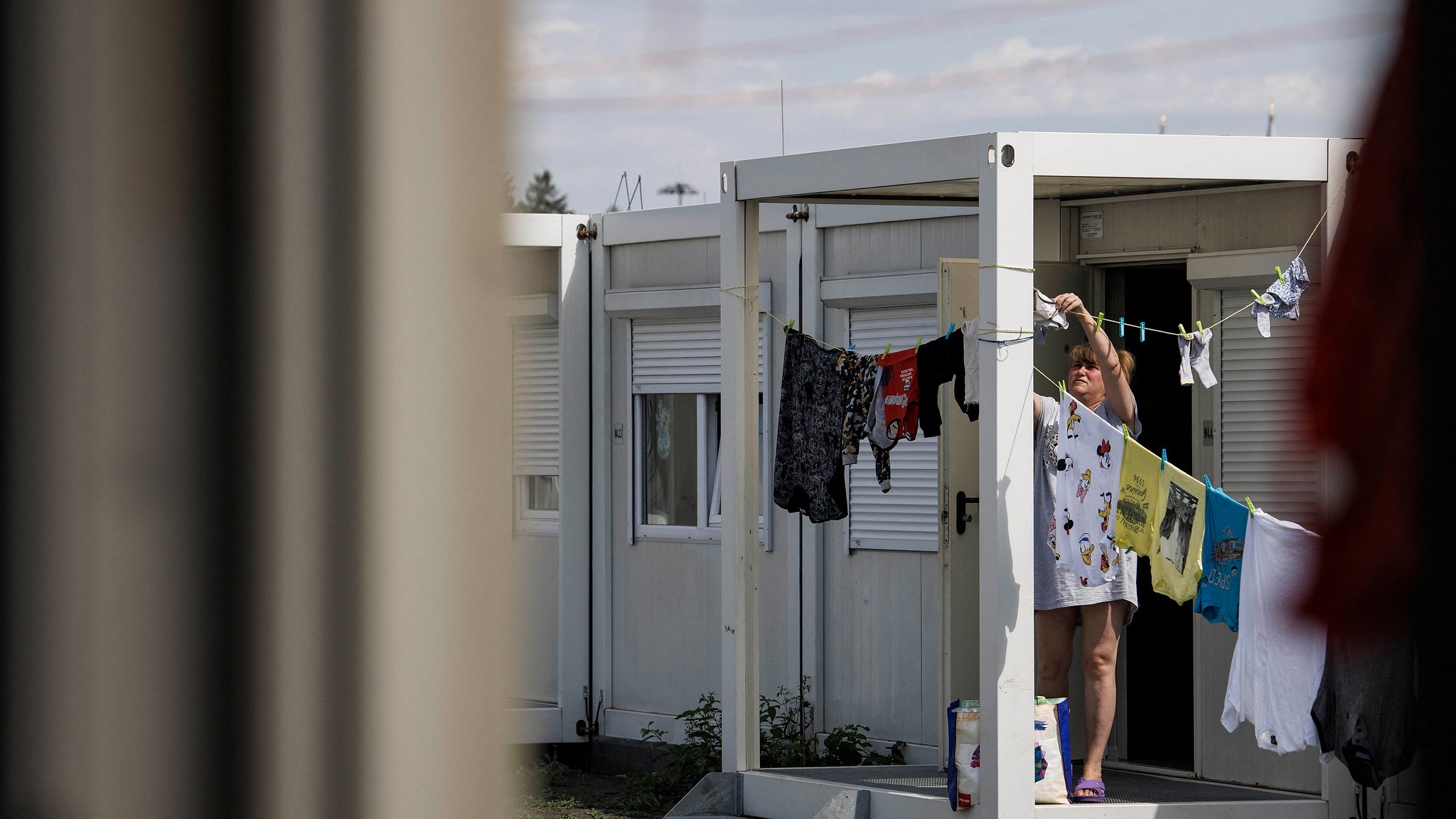 Eine Frau hängt in einem Containerdorf auf dem Tempelhofer Feld in Berlin Wäsche auf.