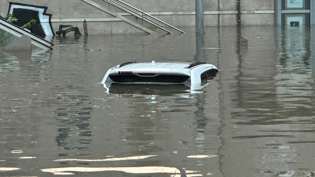 Ein Auto, von dem man nur das Dach erkennen kann, steht in einer überschwemmten Straße an einer Nürnberger Unterführung.