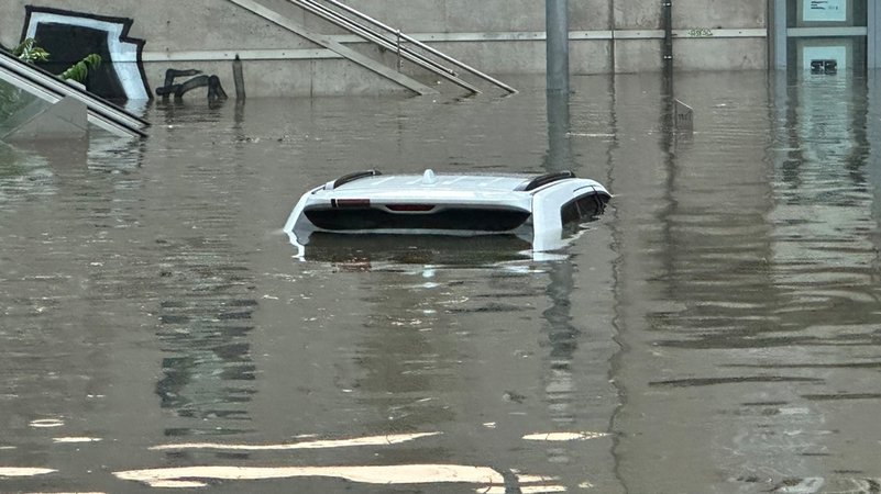 Ein Auto, von dem man nur das Dach erkennen kann, steht in einer überschwemmten Straße an einer Nürnberger Unterführung.