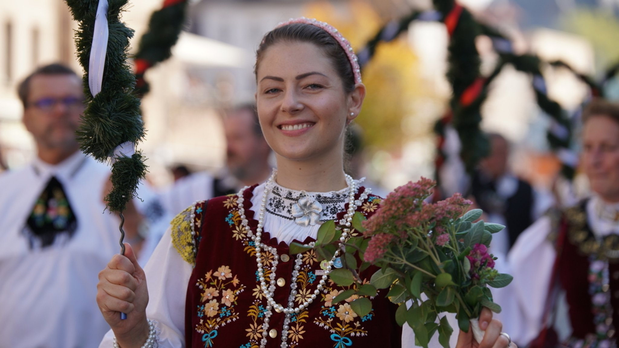 Eine Frau in Tracht trägt Blumen beim Erntedankfestzug.