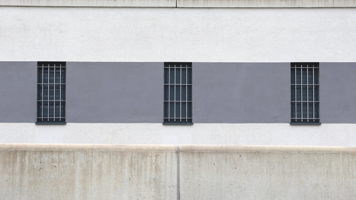 Vergitterte Fenster sind hinter einer Mauer der Justizvollzugsanstalt Gablingen zu sehen.